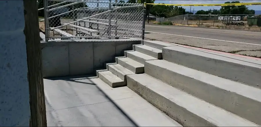 New poured concrete steps and retaining wall leading up to the bleachers at a ballpark