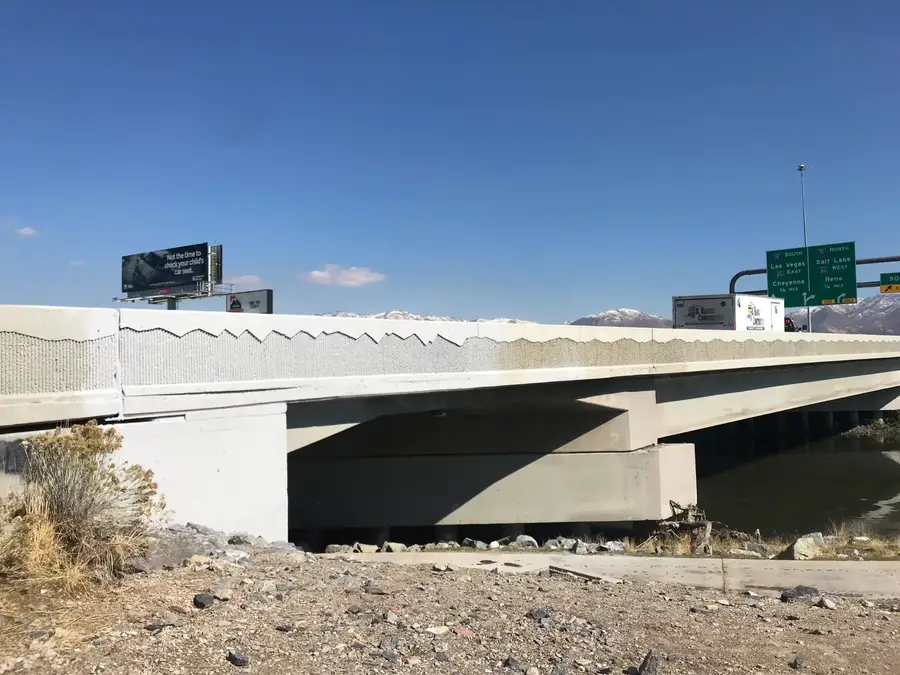 Bridge over a channel with its concrete parapet surface prepared for repair, under a clear blue sky