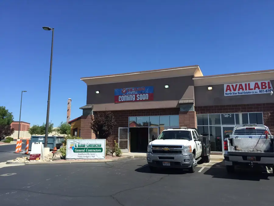 Rumbi Island Grill coming-soon banner on the storefront, with a B Hansen Construction general contractors sign and a work truck out front