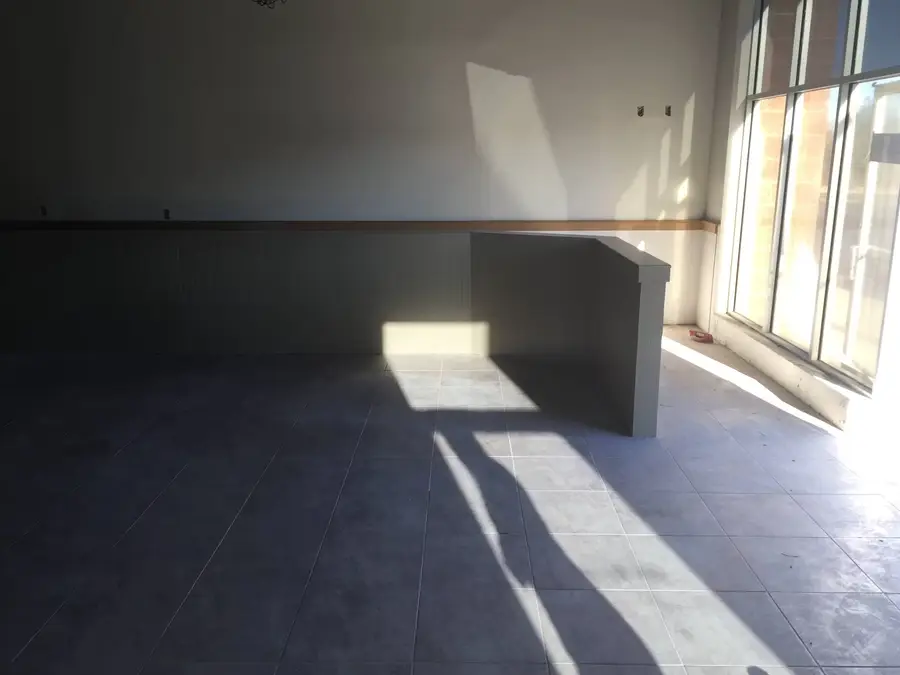 Empty dining area with new tile floor and a half wall lit by sun through the front windows