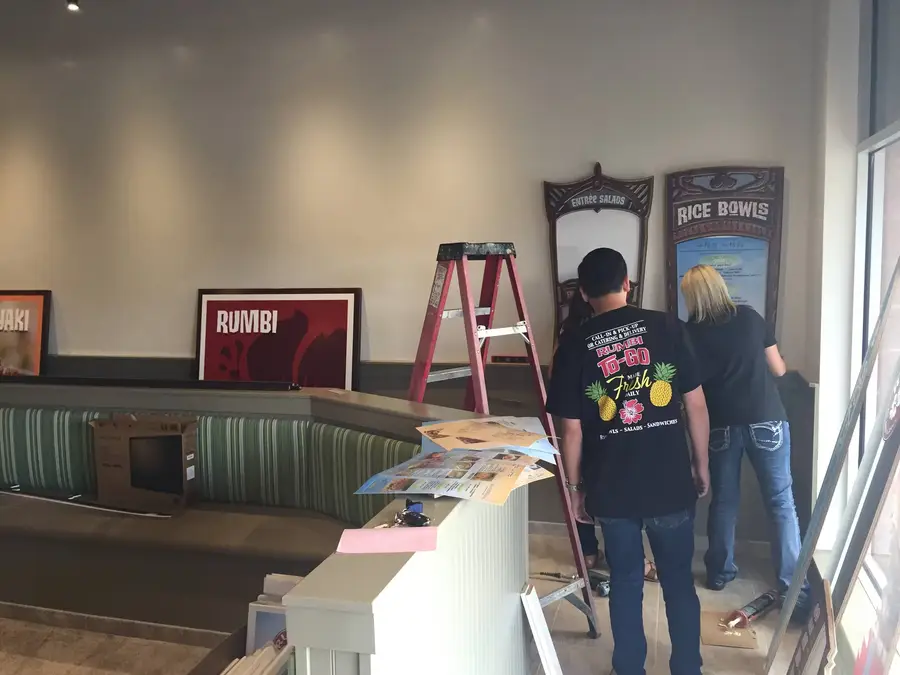 Staff setting up Rumbi menu boards and framed signs in the dining room before opening