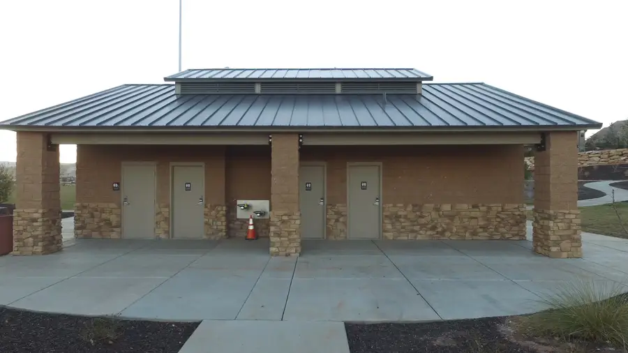 Finished park restroom building with stone-veneer columns, four doors and a standing seam metal roof