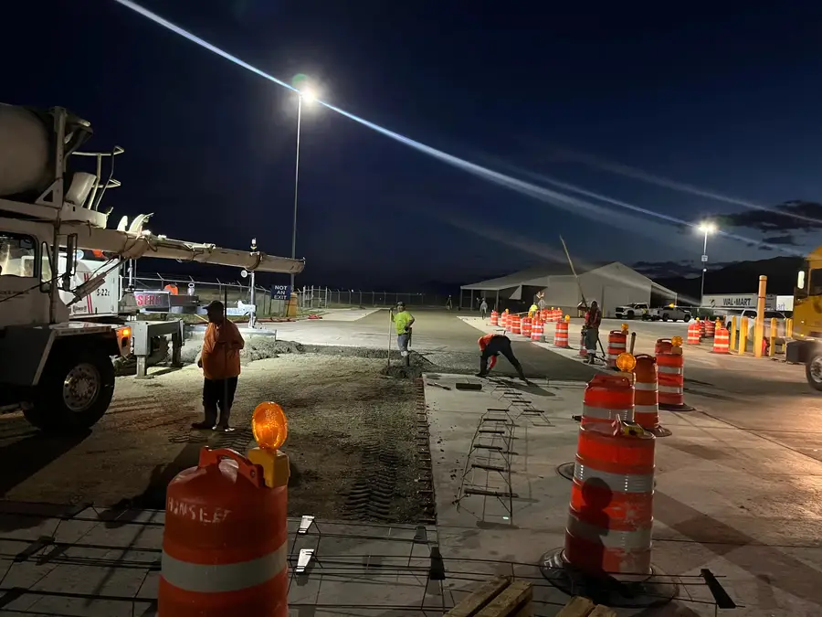 Night crew with traffic barrels and a concrete truck at a Walmart distribution center