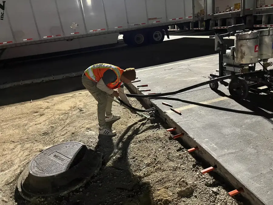 Worker finishing the edge of a new concrete section at a Walmart dock