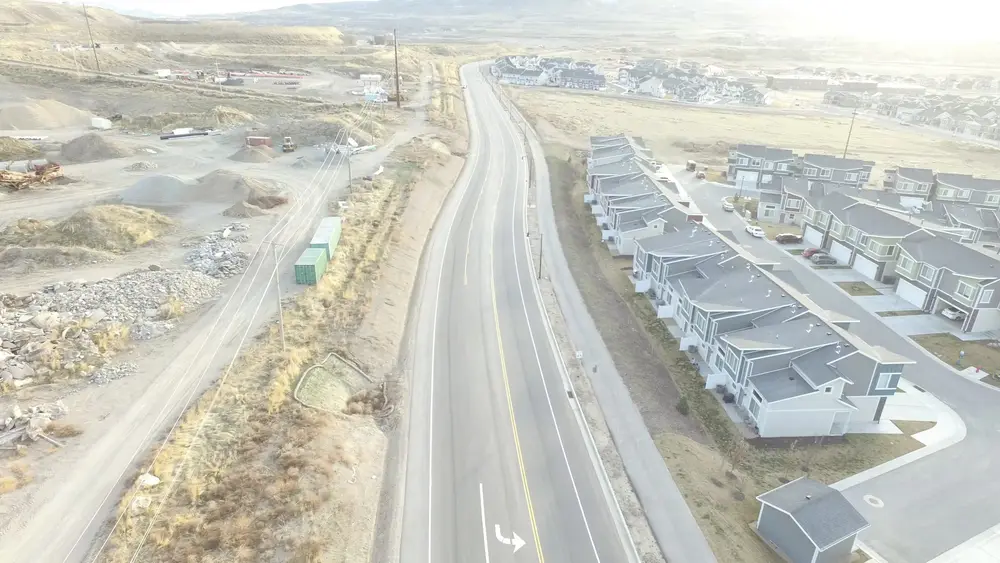 Aerial view of a new road with curb, gutter and sidewalk running past a new neighborhood