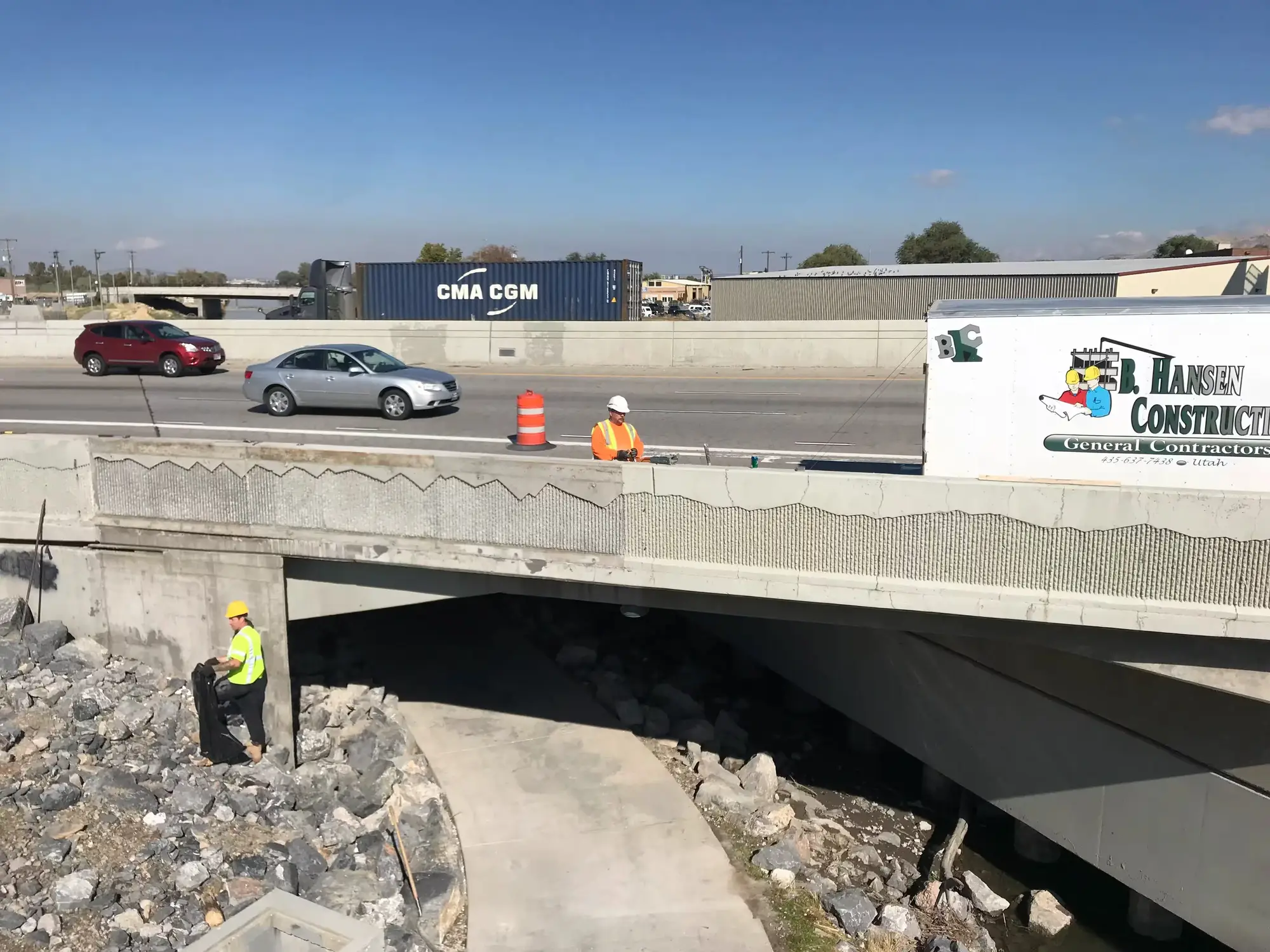 A highway bridge built by B Hansen Construction, with traffic crossing above the crew